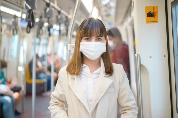 Genç bir kadın metro, covid-19 koruma, güvenlik seyahati, yeni normal, sosyal mesafeler, güvenlik ulaşımı, pandemik konsept altında seyahat ederken koruyucu maske takıyor