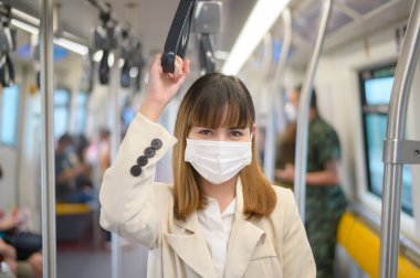 Genç bir kadın metro, covid-19 koruma, güvenlik seyahati, yeni normal, sosyal mesafeler, güvenlik ulaşımı, pandemik konsept altında seyahat ederken koruyucu maske takıyor