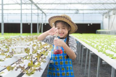 Hidroponik sera çiftliği, eğitim ve bilim adamı konseptinde öğrenim gören mutlu tatlı bir kız.