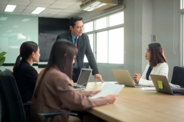 Genç iş adamları modern büroda tartışıyorlar ve beyin fırtınası yapıyorlar.