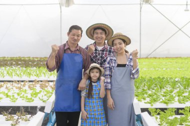 Hidroponik sera çiftliğinde çalışan mutlu bir çiftçi ailesi, temiz yiyecekler ve sağlıklı yeme konsepti.