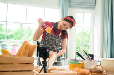 Güzel bir Asyalı kadın evinde fırın yapıyor, canlı yayın yapıyor ya da sosyal medyada video kaydediyor.  