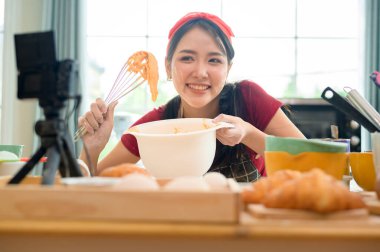 Güzel bir Asyalı kadın evinde fırın yapıyor, canlı yayın yapıyor ya da sosyal medyada video kaydediyor.  