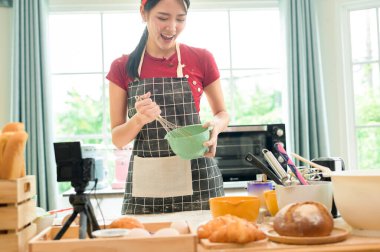 Güzel bir Asyalı kadın evinde fırın yapıyor, canlı yayın yapıyor ya da sosyal medyada video kaydediyor.  