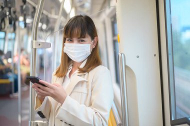 Genç bir kadın metro, covid-19 koruma, güvenlik seyahati, yeni normal, sosyal mesafeler, güvenlik ulaşımı, pandemik konsept altında seyahat ederken koruyucu maske takıyor