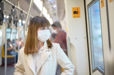 Genç bir kadın metro, covid-19 koruma, güvenlik seyahati, yeni normal, sosyal mesafeler, güvenlik ulaşımı, pandemik konsept altında seyahat ederken koruyucu maske takıyor