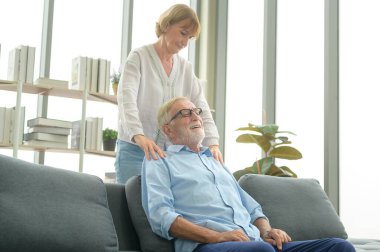 Kafkasyalı kıdemli adam oturma odasında karısına masaj yapıyor.