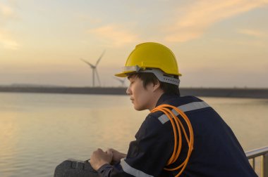 A male engineer wearing a protective helmet at sunset.	