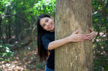 Ormanda büyük bir ağaca sarılan genç bir kadın, çevre ve koruma kavramı