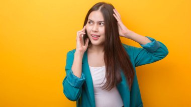 Sarı arka planda cep telefonu kullanan yeşil takım elbiseli güzel bir kadının moda portresi. 