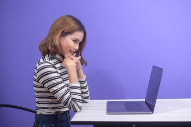 A young beautiful woman is working with her computer over blue background.	