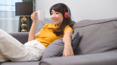 Genç ve mutlu bir kadın müzik dinliyor ve evde dinleniyor.