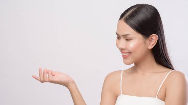 Beyaz arka planda pürüzsüz, sağlıklı bir teni olan genç ve güzel bir kadının portresi.