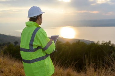 Bir insan mühendisi kafasına koruyucu bir kask takıyor. Tablet Analitik Mühendisliği verilerini kullanıyor..