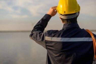 A male engineer wearing a protective helmet at sunset.	