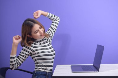 Genç kadın bilgisayarla sıkı çalıştıktan sonra dinleniyor. 