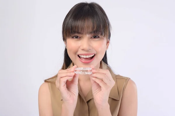 一名年轻的微笑女性 在白色背景工作室 牙齿保健和牙齿矫正的概念下 手持无创矫形器架 — 图库照片