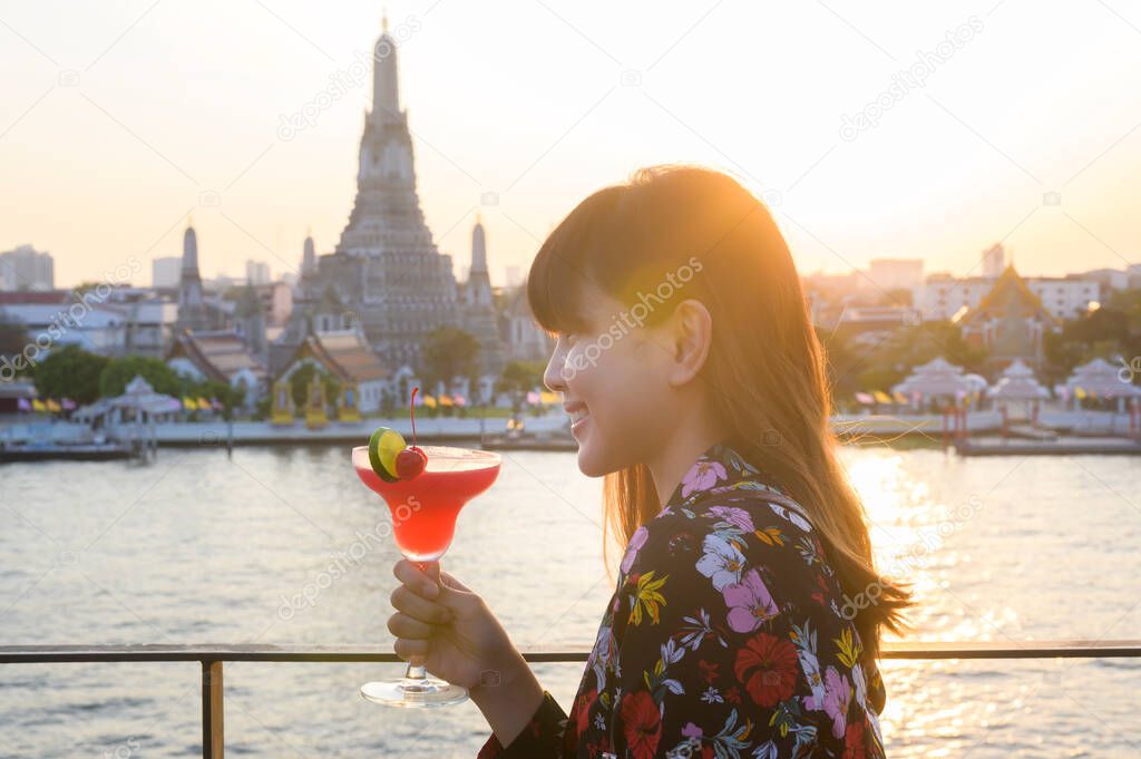 A woman tourist drinking cocktail over Bangkok cityscape 