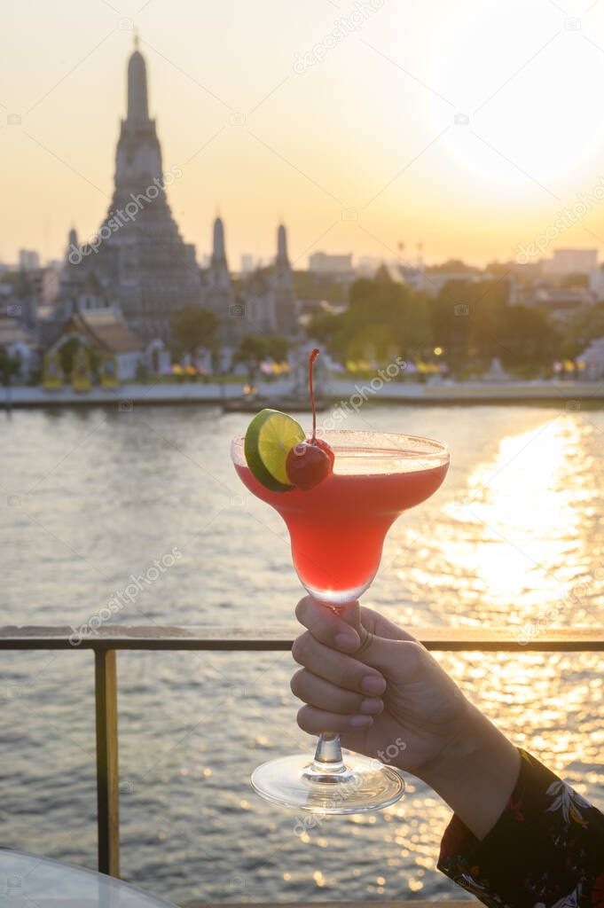 A woman tourist drinking cocktail over Bangkok cityscape 