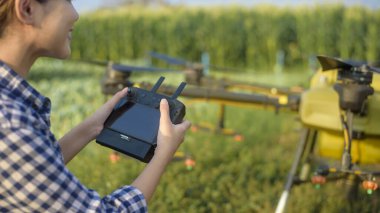 Genç ve zeki bir çiftçi İHA 'yı kontrol ediyor gübre ve böcek ilacını tarım arazisi, yüksek teknoloji yenilikleri ve akıllı tarım üzerine püskürtüyor.