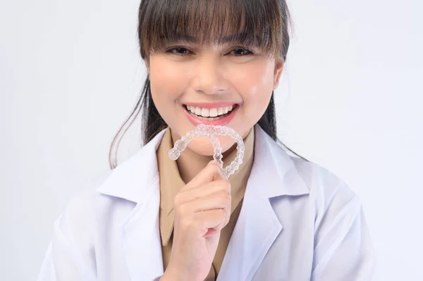 一名年轻的女牙医在白人背景演播室 牙科保健和牙齿矫正概念的基础上 手持无创矫形器架 — 图库照片