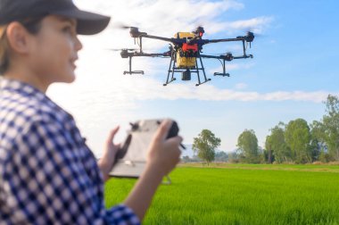 Genç ve zeki bir çiftçi İHA 'yı kontrol ediyor gübre ve böcek ilacını tarım arazisi, yüksek teknoloji yenilikleri ve akıllı tarım üzerine püskürtüyor.