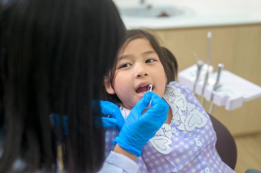 Dişçi kliniğinde dişlerini kontrol ettiren küçük tatlı bir kız diş kontrolü ve sağlıklı diş konsepti.