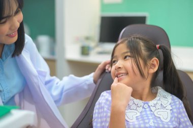 Dişçi kliniğinde dişlerini kontrol ettiren küçük tatlı bir kız diş kontrolü ve sağlıklı diş konsepti.