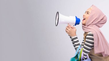 Takım elbiseli güzel bir müslüman kadın beyaz arka plan stüdyosunun üzerinde renkli alışveriş çantaları taşıyor.