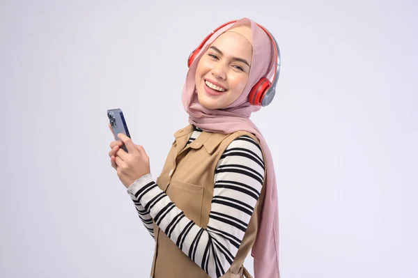 一位年轻漂亮的穆斯林女子 头戴白色背景的耳机 — 图库照片