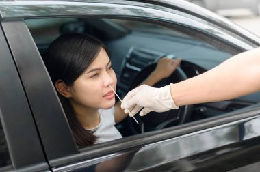 Arabada oturan bir kadın Drive-Thru COVID-19 Test, sağlık ve güvenlik testinde test yaptırıyor.