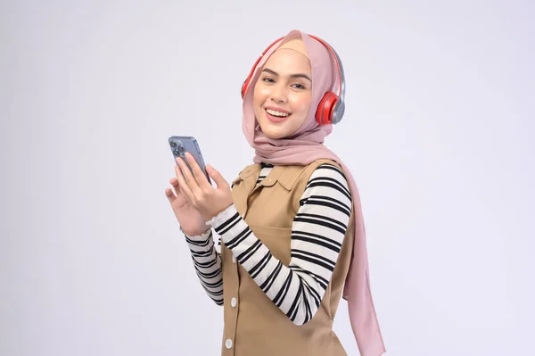 一位年轻漂亮的穆斯林女子 头戴白色背景的耳机 — 图库照片