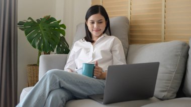 Genç ve güzel bir kadın evde bilgisayarıyla çalışıyor..