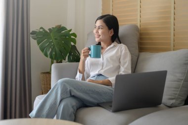 Genç ve güzel bir kadın evde bilgisayarıyla çalışıyor..