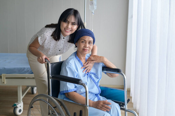 Cancer patient woman wearing head scarf and her supportive daughter in hospital, health and insurance concept.