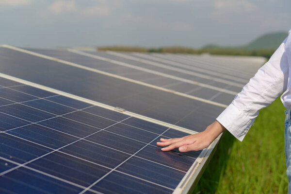 Крупный план ручного инженера, касающийся фотоэлектрической клеточной фермы или поля солнечных панелей, экологически чистой энергии.