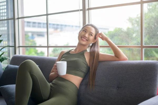 スポーツウェアを着た若いフィットネス女性は 自宅で運動した後にコーヒーを飲みます 健康とライフスタイル — ストック写真