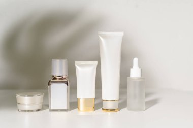 Beyaz arka plan stüdyosunun üzerinde nemlendirici krem şişesi, paketleme ve cilt güzellik konsepti