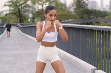 Şehir parkında spor giyim boksu yapan sağlıklı ve yaşam tarzı olan genç bir fitness kadını..