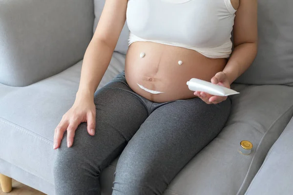 在肚子 保健和孕期护理中使用润肤霜的年轻孕妇 — 图库照片