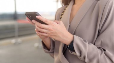 İş kadını eli modern şehirde akıllı telefon kullanıyor.