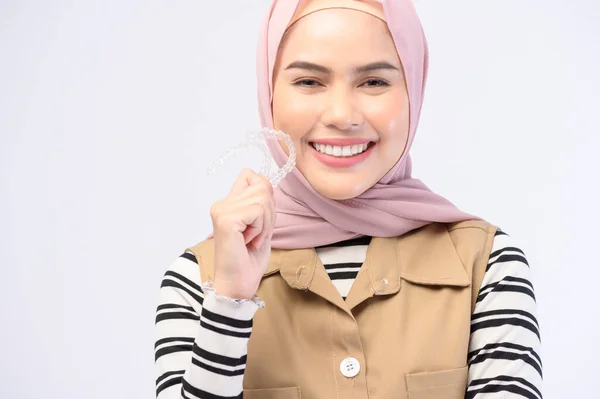 スタジオ 歯科医療 歯列矯正の概念でInvisalineブレースを保持している若いイスラム教徒の女性 — ストック写真