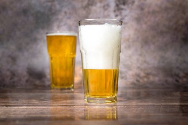 Soğuk hava hafif birası şişeden dökülüyor ahşap masa üzerine 