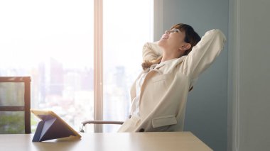 Güzel bir iş kadını modern ofiste rahatlıyor ve esniyor.