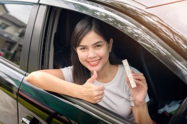 ATK 'yi arabada tutan bir kadın COVID-19 testi, sağlık ve güvenlik testleri için kendi kendini tahsilat testi yapar.