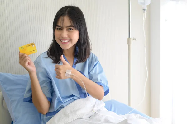 A young patient woman is holding credit card , admitting in hospital , Health care  concept