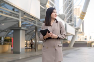 Genç ve güzel bir iş kadını modern şehirde tablet kullanıyor, iş teknolojisi, şehir yaşam tarzı konsepti. 