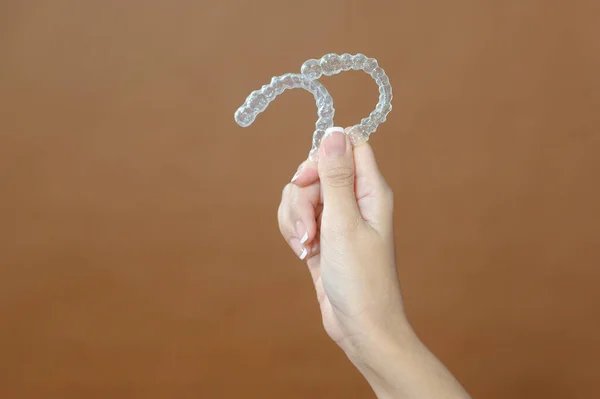Close Young Woman Hand Holding Invisalign Brown Background — Stok Foto