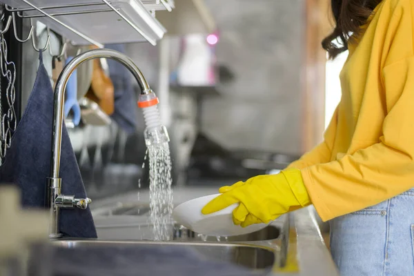 黄色の手袋を身に着けている若い幸せな女性台所で食器洗い機自宅で — ストック写真