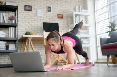 Profesyonel eğitmen, spor ve sağlıklı yaşam tarzı konseptiyle çevrimiçi kurs yoluyla evde yoga yapan sağlıklı genç bir kadın..